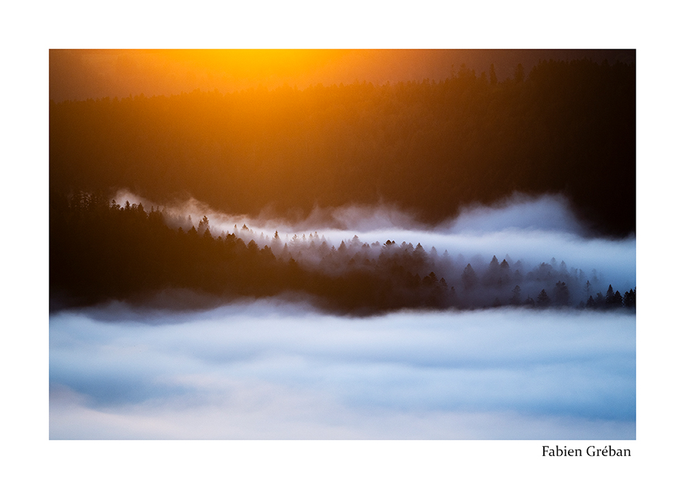 photographie de paysage sur les sommets du massif du Jura au dessus de la mer de nuage, contraste des tons chaud du lever du soleil et des tons froids de la brume dans la valle